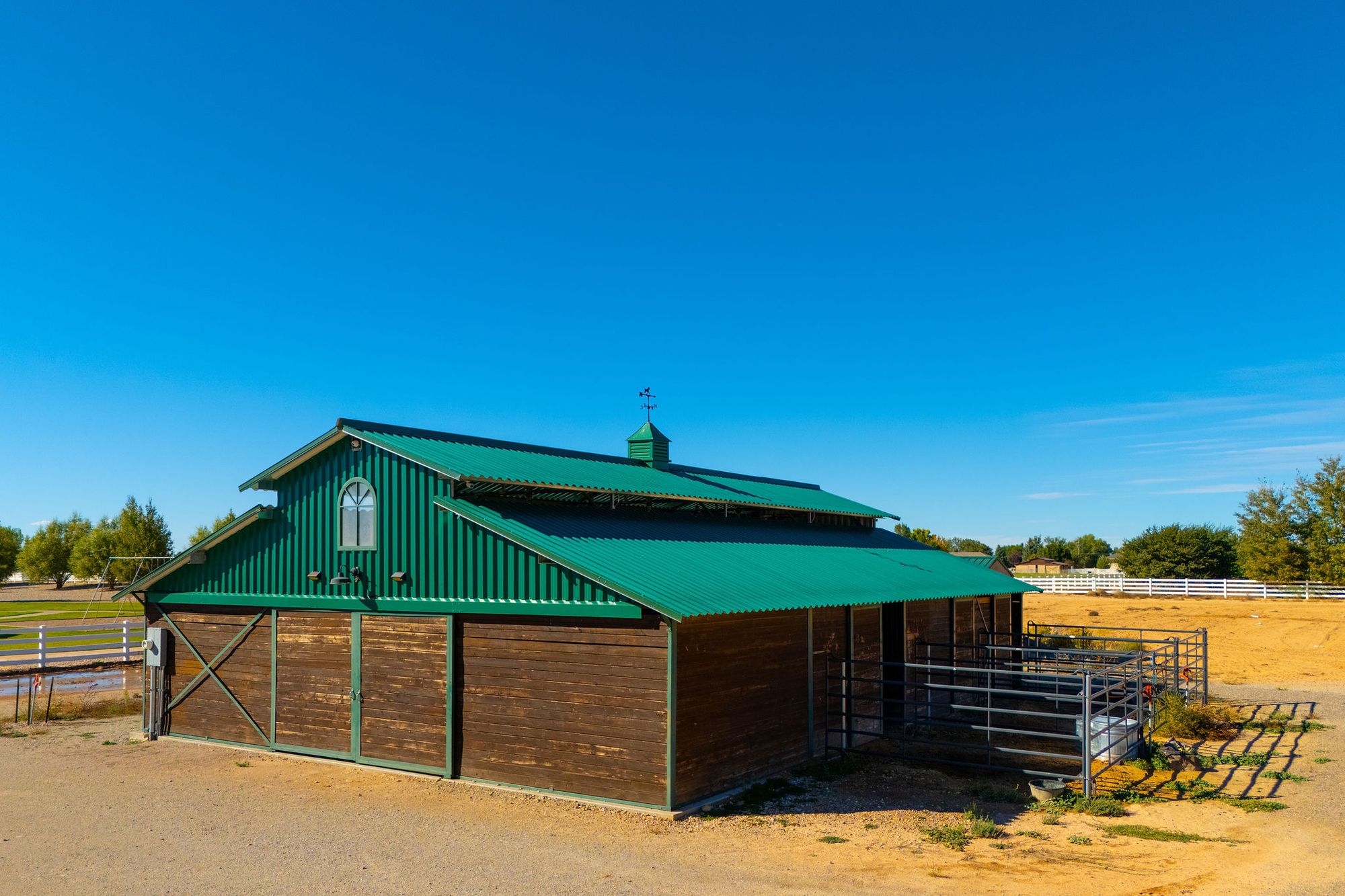 The Equestrian Pointe stables — a timber barn with a green metal roof